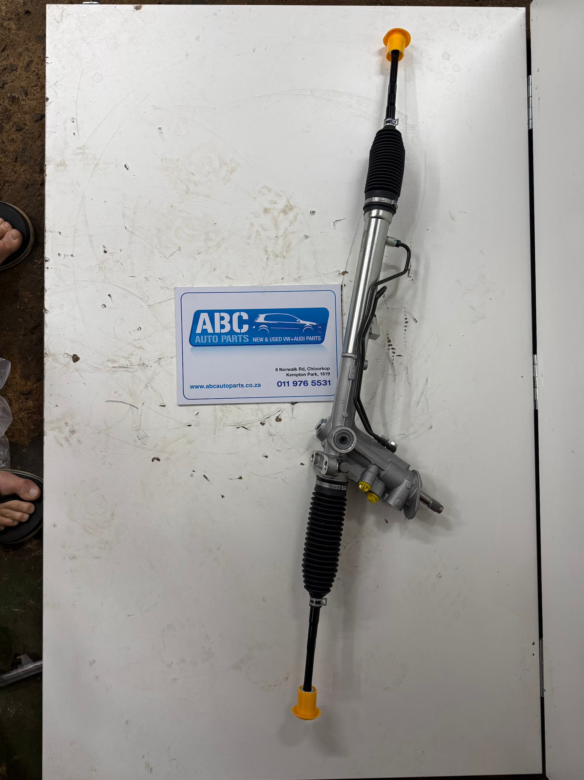 Mechanical steering component on a white surface with ABC Auto Parts branding.