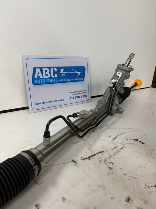 Car steering rack on a white surface with ABC Auto Parts sign in the background