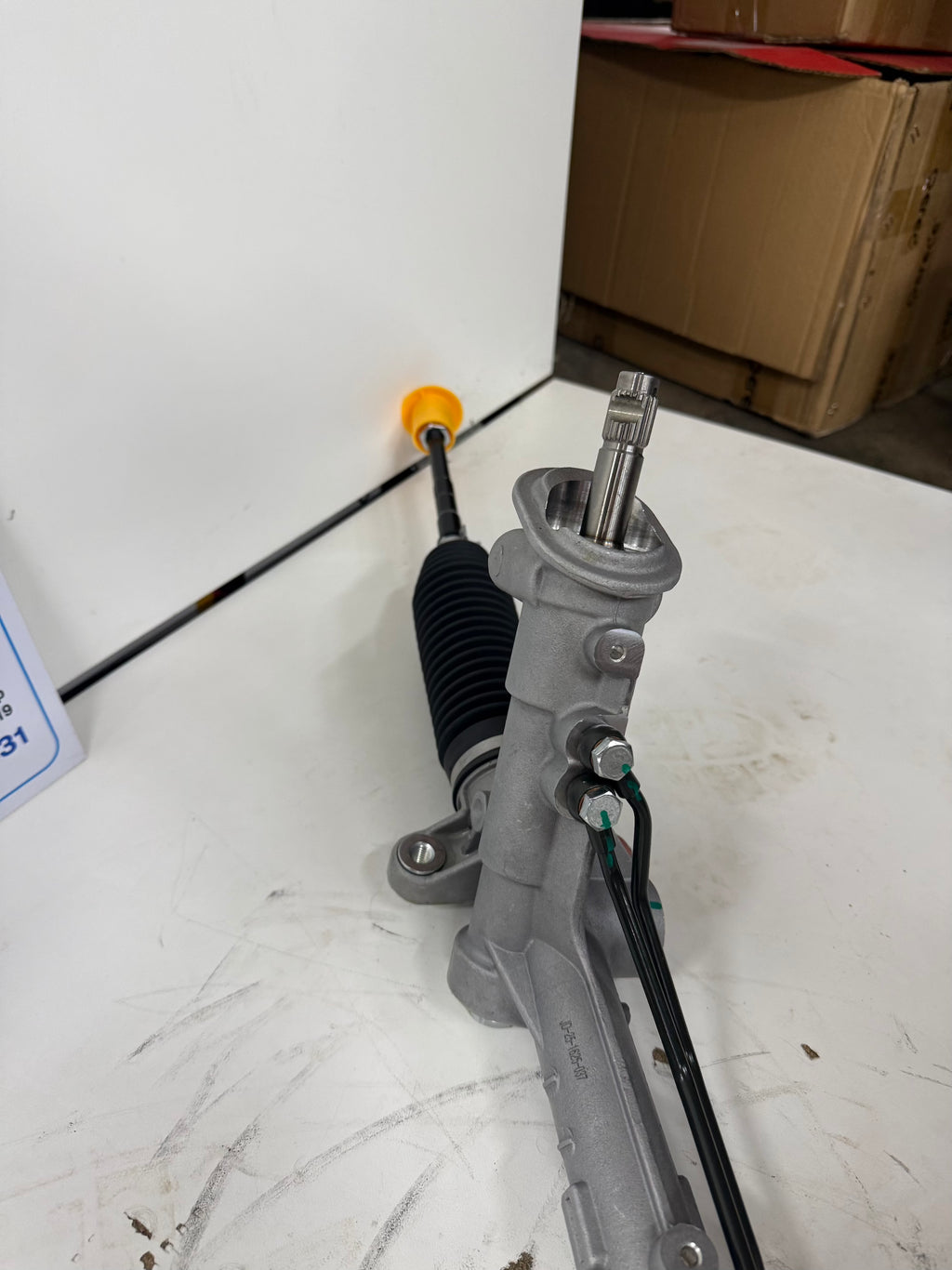 Mechanical steering component on a white surface with cardboard boxes in the background
