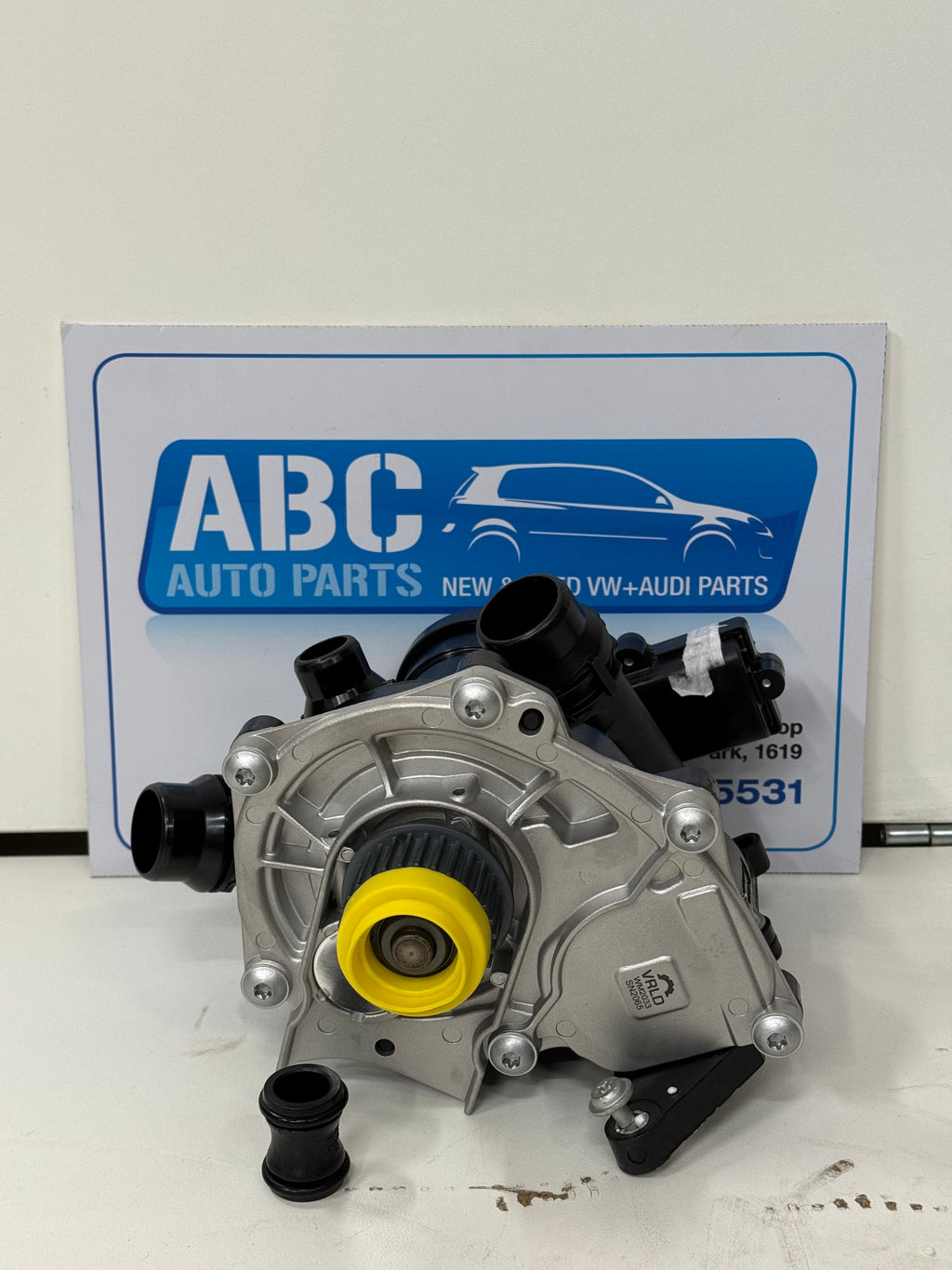 Mechanical part with yellow component on a white surface, branded 'ABC Auto Parts'.